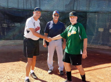 Managers Steve Hilby of Terry & Susan Young’s West USA Realty team and Ken Brenden of Brenden Financial Services meet before a recent game as umpire Gary Hillabolt looks on.