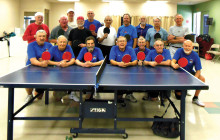 The victorious Saddlebrooke team displays the red paddles. The Sun Lakes Table Tennis Club members display the black paddles.