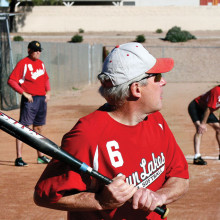 Bill Cheney is ready to swing away during a recent contest. In the background is third base coach Evan Hansen and base runner Larry Maggerd. (Photo courtesy of Core Photography)