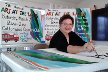 Susan Plouzek paints signs for Art at the Lakes in her studio.