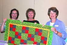 Gwen Oberg, Jean Larson and Sherri Tanner hold one of the kids quilts headed to hospitals.