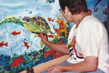 Bev Walter works on a mural at The Center Against Family Violence.
