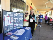 Raffle coordinator Betty Sanders and IronOaks Tennis Club President Judy Gahide raising money for Neighbors Who Care.