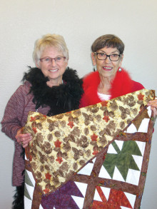 Sue Niesz, left, and Barb Dubler of Sun Lakes display a hand-stitched quilt made by the Chandler Senior Center Quilters Group which will be one of the items for auction at the April 16 fashion show and luncheon for Assistance League of East Valley.