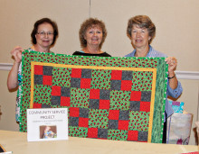 The Agave community service team shows off one of the many children’s quilts donated by members.