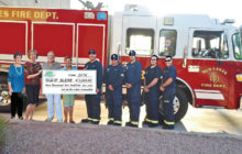 Sun Lakes Emergency Relief Fund check is presented to firefighters. Pictured left to right are Pat Merkle, Diane Hitt, Gary Neffenger, Susan Plouzek, Brandon Johnson, Martin Lain, Andrew Craker, Ari Barr and Nate Van Briesen.
