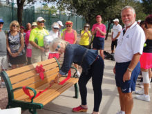 Sandy Neu cuts ribbon on dedicated bench as project coordinator, Bruce Stead, looks on