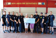 Sun Lakes Lady Niners Secretary/Party Chair Sheila Barton and 1st Vice President Celeste Dorsey present a check for $3,000 to the Sun Lakes fire district, including Chief Troy Maloney and Deputy Chief Rob Helie and the on-duty firefighters and medics from the SLFD’s stations.