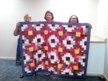 Betty Peer, Janice Cournoyer and Stephanie Reynolds of Post 8053 Auxiliary with an Arizona Quilt Crew quilt. The quilt was pieced and donated by Torrie Malone, a friend of the group, and quilted by Kay Rapp, a member of the group.