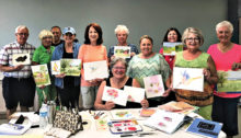 Jean Anderson (seated) with students in her beginning watercolor class displaying examples of their work