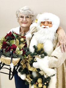 Phyllis Hesselrode of Sun Lakes, chairperson of the Holiday Happenings event for Assistance League of East Valley, shares a hug with a five-foot-tall Santa, which will be among the decorations for sale.