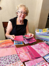 Working at home, Bobbie Reed chooses colorful trim paper for creating Crystal Cards.