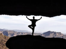 Yoga student Bill Gosiak practicing Tree pose next to a cave on one of the hiking trails near Superstition Mountain