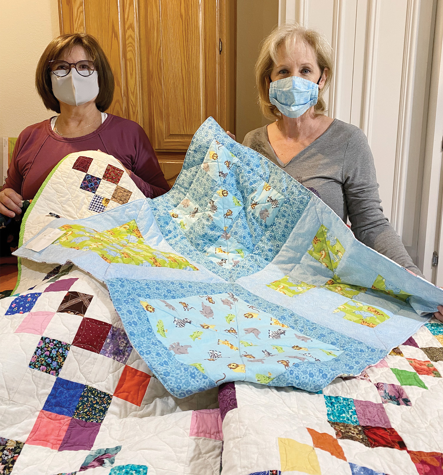 Blanca Sanchez and Jody Edwards hold a few of the colorful quilts made for children in area shelters.